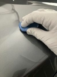 Technician safely removing paint overspray from car panel using clay bar and lubricant – Gold Coast mobile detailing