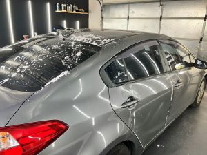 "Kia Cerato undergoing decontamination in workshop, with chemical treatment softening calcium deposits on the surface."