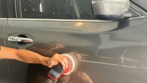Detailer using a dual-action polisher on a dark car door panel during high gloss car polishing Gold Coast service to remove imperfections and enhance shine.